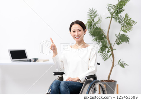 Woman in wheelchair working from home pointing 125453599