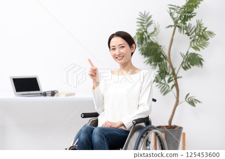 Woman in wheelchair working from home pointing Woman in wheelchair working from home pointing 125453600