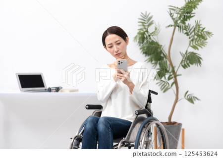 坐輪椅的女性在家使用智慧型手機工作時擔心 125453624