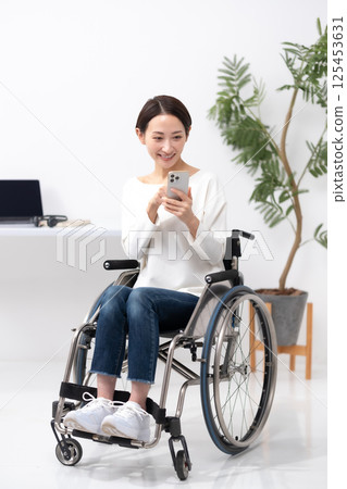Woman in wheelchair working from home smartphone Woman in wheelchair working from home smartphone 125453631