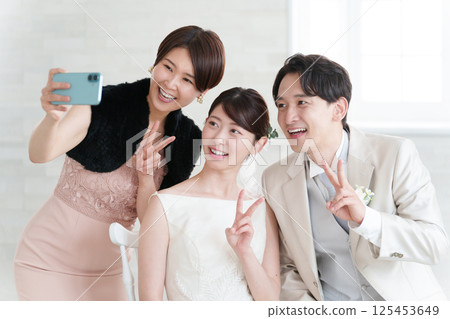 Bride and groom photographed with wedding guests 125453649