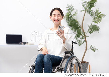 坐輪椅的女人在家工作，用智慧型手機 125453675