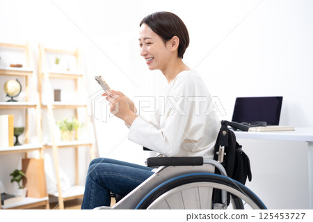 Woman in wheelchair, smartphone 125453727