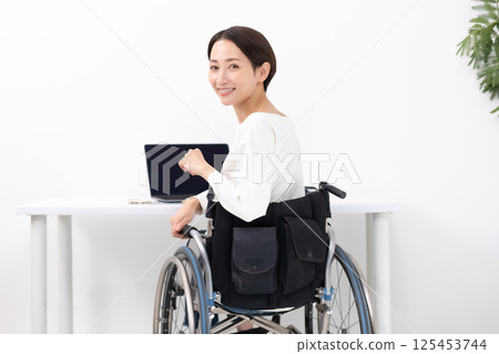 Woman in wheelchair working from home 125453744