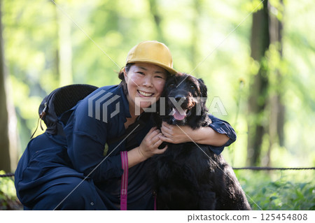 A woman walking a dog, a friendly image of a dog trainer and owner, looking at the camera 125454808
