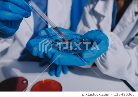 Researcher using a professional microscope Researcher using a professional microscope 125456363