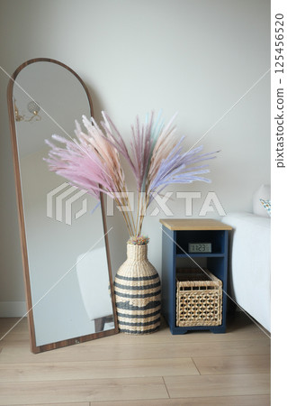 Stylish indoor decor featuring a tall mirror and colorful pampas grass 125456520