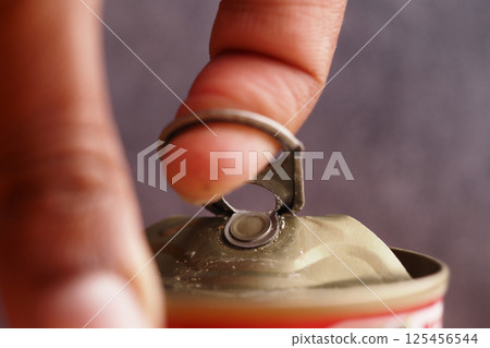 Opening a beverage can with a metal tab using a finger 125456544