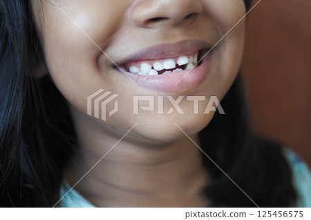 Child smiles showing gap between teeth in casual indoor setting 125456575