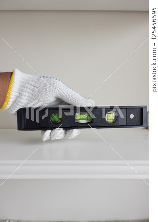 Leveling tool held by hand checks alignment on shelf Leveling tool held by hand checks alignment on shelf 125456595