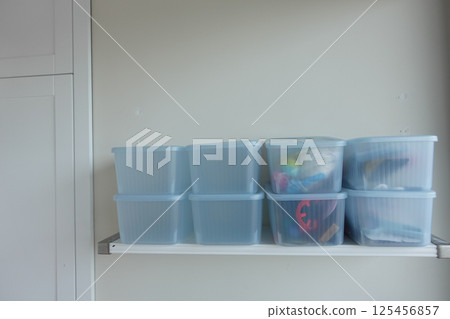 Organizing clear storage containers on a minimalist shelf 125456857