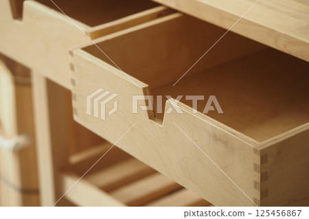 Wooden drawer partially opened in a minimalist workspace 125456867