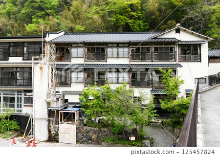 [Oguni Town: The exterior of the traditional Japanese inn Izumiya, seen from Sakura Bridge in Tsuetate Onsen, the No. 1 carp streamer village in Japan] 125457824