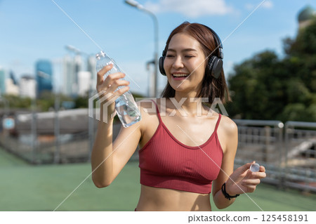 Asian young female sporty drinking water from water bottle while exercising. stay hydrated per day. Healthy fit woman fresh wellness. Drinking water makes you feel good. 125458191