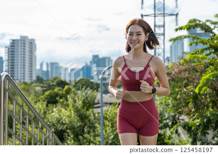 Young beautiful woman sportswear workout clothes exercise running street city park before morning run. Asian strong female sporty sportswear jogging outdoors. fitness healthy concept. 125458197