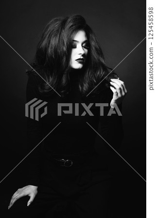 Beautiful woman with long dark hair black and white studio portrait Beautiful woman with long dark hair black and white studio portrait 125458598