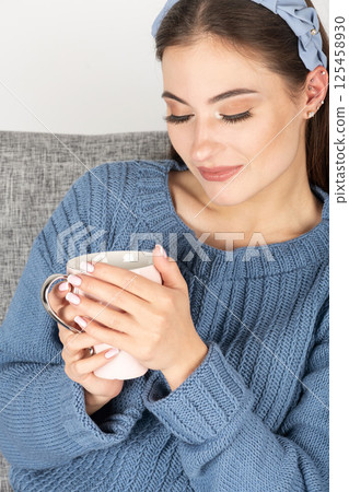 Beautiful woman with sweater holding cup in her hands 125458930
