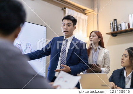 Group of professionals engaged in business meeting, discussing financial reports and charts while in contemporary office setting. Brainstorming and analyzing statistics and company growth graphs 125458946
