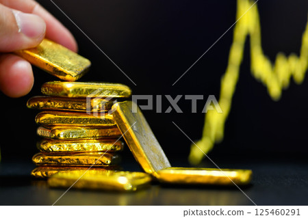 Close up photo hand holding a gold bars the candlestick chart.  background , Fluctuations in gold prices concept. 125460291