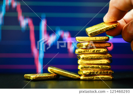 Close up photo hand holding a gold bars the candlestick chart.  background , Fluctuations in gold prices concept. 125460293