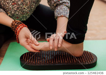 The therapist kneads the patient's leg. A woman tries to stand on nails 125461436