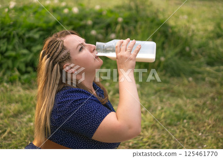 A woman blissfully enjoying a refreshing drink while immersed in the beauty of nature outside A woman blissfully enjoying a refreshing drink while immersed in the beauty of nature outside 125461770
