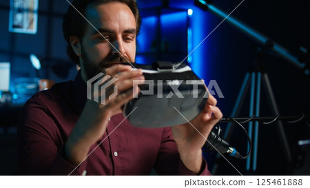 Focus on smartphone attached to tripod used by online star in blurry background discussing with viewers. Mobile phone used by influencer to record social media video, camera B close up 125461888