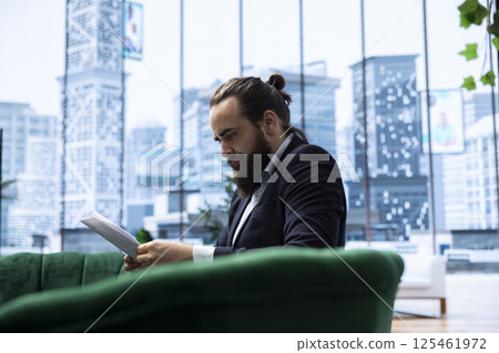 Young business director reviews sales trends and budget reports in his smart office, ensuring profitability and company success through effective decision making and strategic planning. 125461972