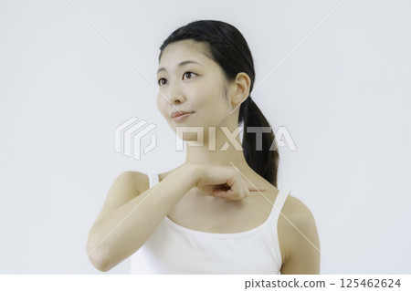 Close-up of a young woman's face pressing acupressure points on her shoulder against a white background Close-up of a young woman's face pressing acupressure points on her shoulder against a white background 125462624