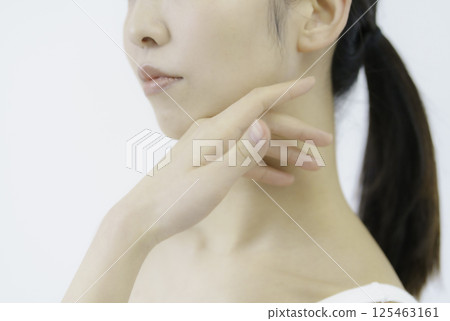 Close-up of a young woman's face with her hand on her cheek against a white background 125463161