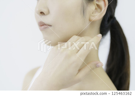 Close-up of a young woman's face with her hand on her cheek against a white background 125463162