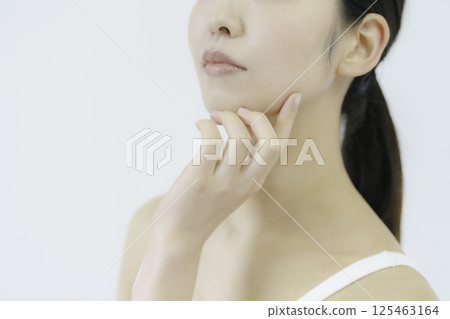 Close-up of a young woman's face with her hand on her cheek against a white background Close-up of a young woman's face with her hand on her cheek against a white background 125463164