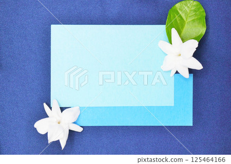 A mockup of a title frame in cool colors with lovely jasmine flowers decorated on a navy cloth background A mockup of a title frame in cool colors with lovely jasmine flowers decorated on a navy cloth background 125464166