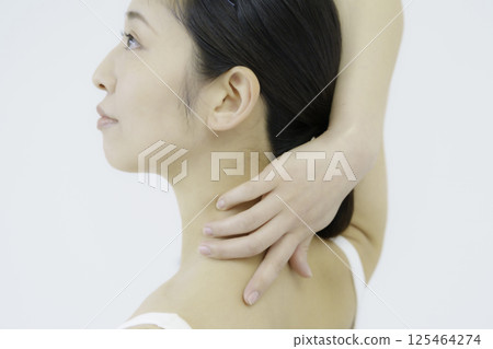 Close-up of a young woman's face touching her nape against a white background 125464274
