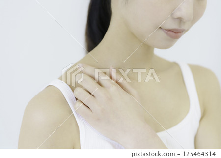 Close-up of a young woman's face pressing acupressure points on her shoulder against a white background Close-up of a young woman's face pressing acupressure points on her shoulder against a white background 125464314