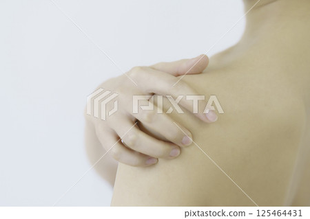 Close-up of a young woman's face holding her shoulders against a white background 125464431