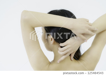 Back view of a young woman touching her nape against white background Back view of a young woman touching her nape against white background 125464543