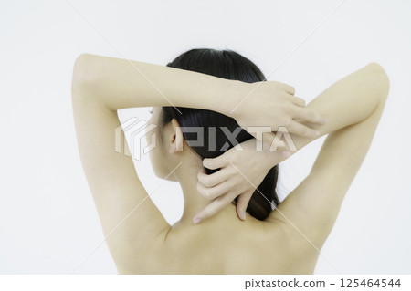 Back view of a young woman touching her nape against white background 125464544