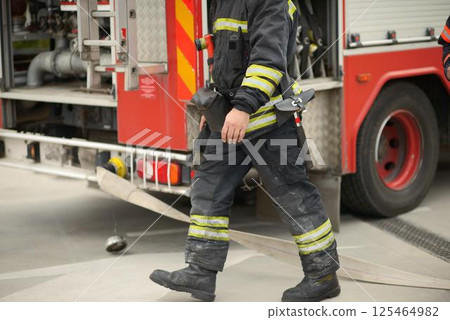 Firefighter Near Fire Truck With Deployed Hose Firefighter Near Fire Truck With Deployed Hose 125464982