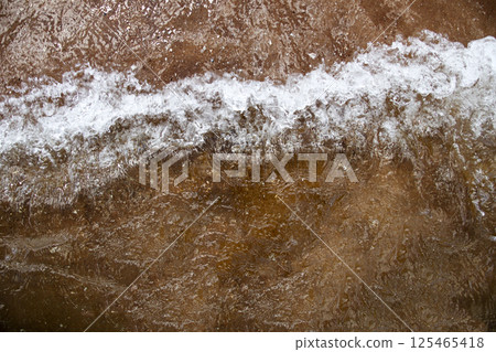 Brown sea waves rolling gently, creating a natural texture of water movement and earthy tones. serene coastal scene with soft wave patterns. Sea storm background 125465418