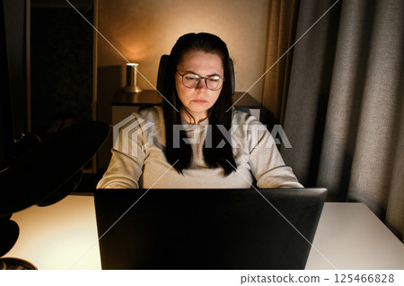 Woman working on computer late evening at home office. Concentrated female freelancer trying to solve business problems. Working and suffering from weariness. Woman working on computer late evening at home office. Concentrated female freelancer trying to solve business problems. Working and suffering from weariness. 125466828
