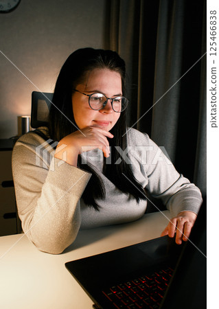 Smiling millennial girl sitting at desk with computer scrolling internet, doing online shopping. Working on laptop in home office. Freelance work at home. Smiling millennial girl sitting at desk with computer scrolling internet, doing online shopping. Working on laptop in home office. Freelance work at home. 125466838