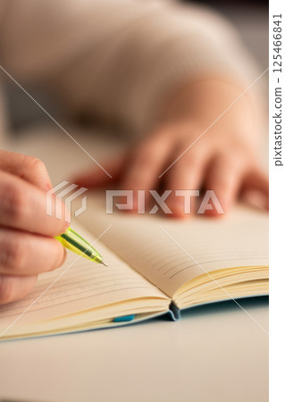 Warm toned image of hand writing personal thoughts in diary. Blurred background for cozy atmosphere. 125466841