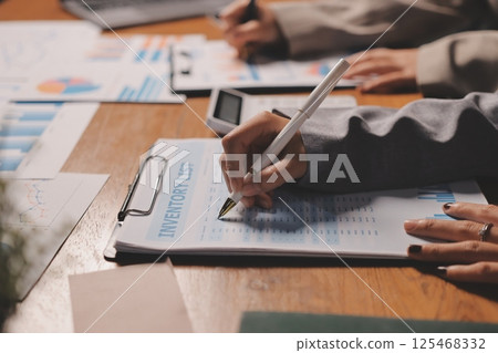 Group of confident business people point to graphs and charts to analyze market data, balance sheet, account, net profit to plan new sales strategies to increase production capacity. 125468332