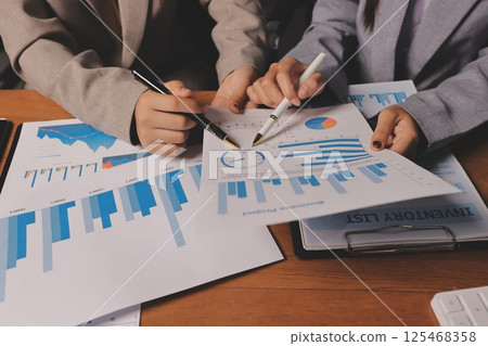 Group of confident business people point to graphs and charts to analyze market data, balance sheet, account, net profit to plan new sales strategies to increase production capacity. Group of confident business people point to graphs and charts to analyze market data, balance sheet, account, net profit to plan new sales strategies to increase production capacity. 125468358