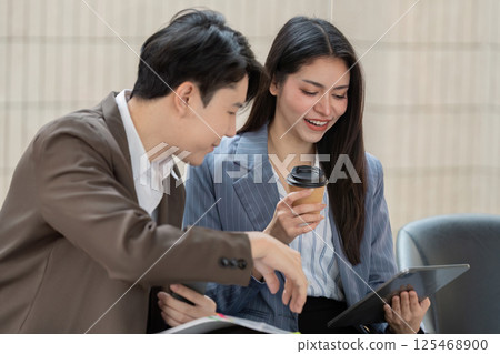 Business professionals collaborating and discussing project plans while enjoying coffee in a modern office. 125468900