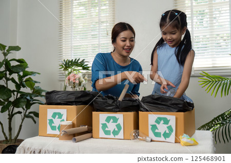 Sustainability and Eco-Friendly Practices. A mother and daughter sorting recyclables together. 125468901