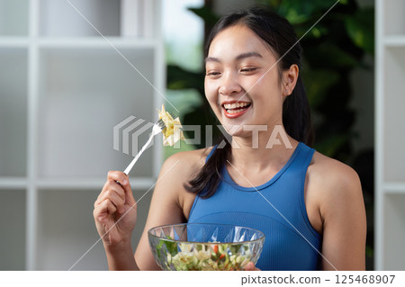 Happy woman enjoying a healthy salad in an indoor setting. 125468907