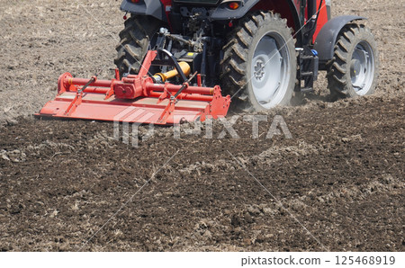 A cultivator (tractor) plowing a rice field in spring 125468919