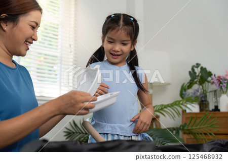 Sustainability Education and Family Values. A mother and daughter explore recyclable materials with a smile. Sustainability Education and Family Values. A mother and daughter explore recyclable materials with a smile. 125468932